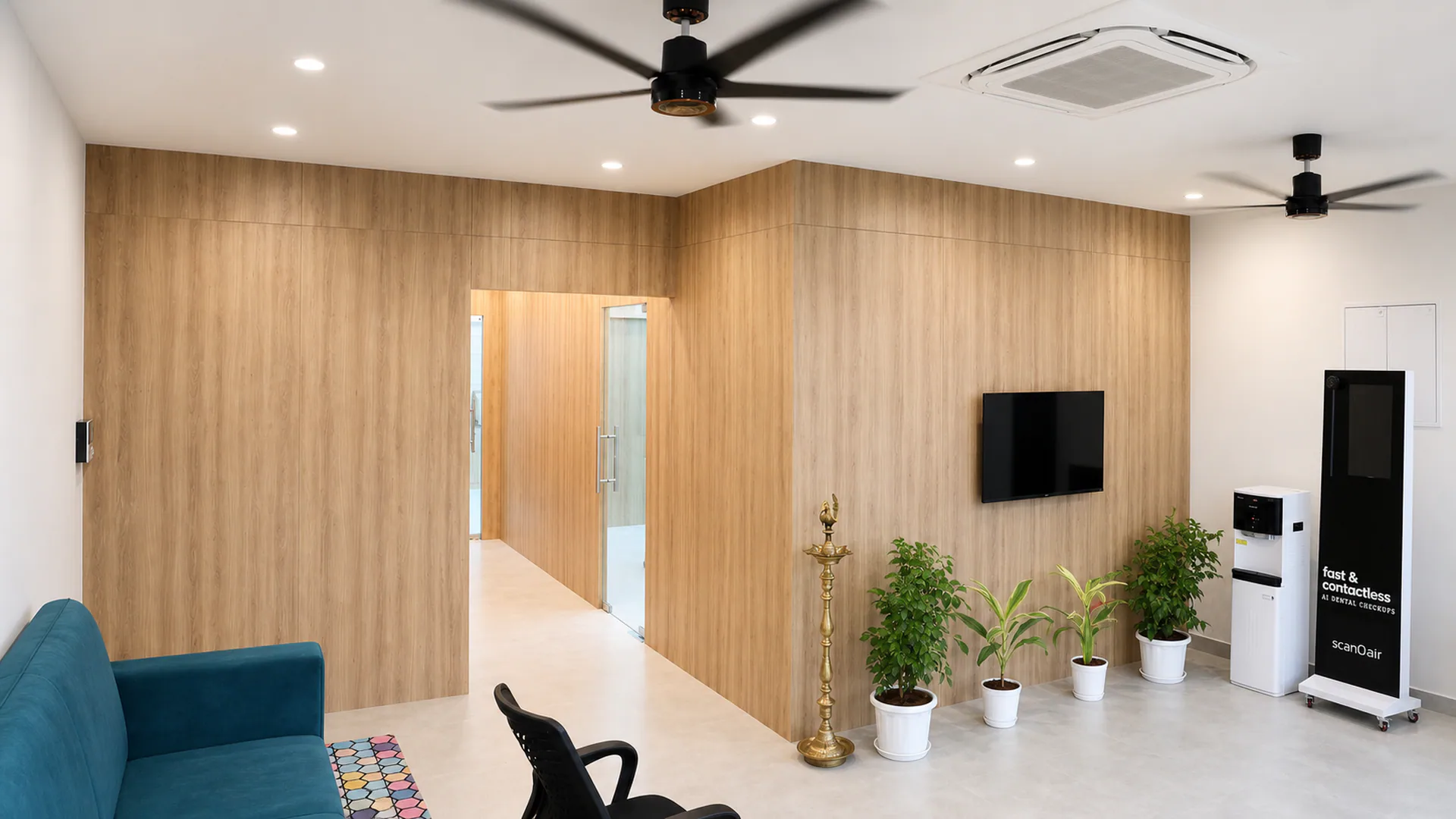 Wood-finished interior wall framing a doorway, television, indoor plants and reception seating.