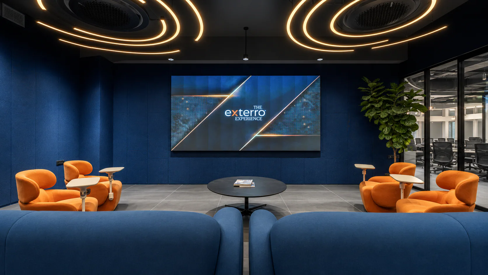 Informal presentation lounge with orange chairs, blue seating and an Exterro display screen.