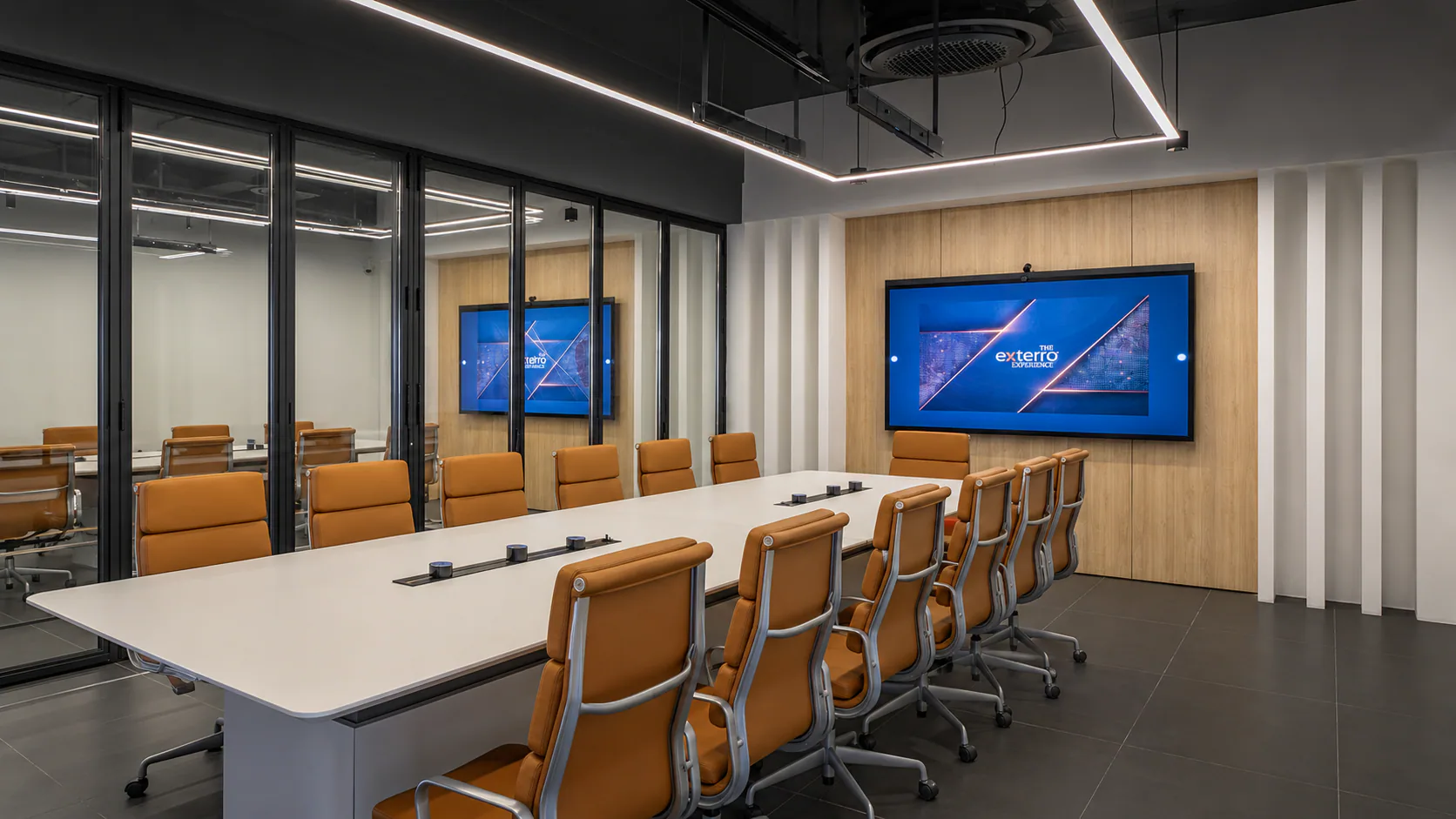Conference room with a long table, orange chairs and a wall-mounted Exterro display.