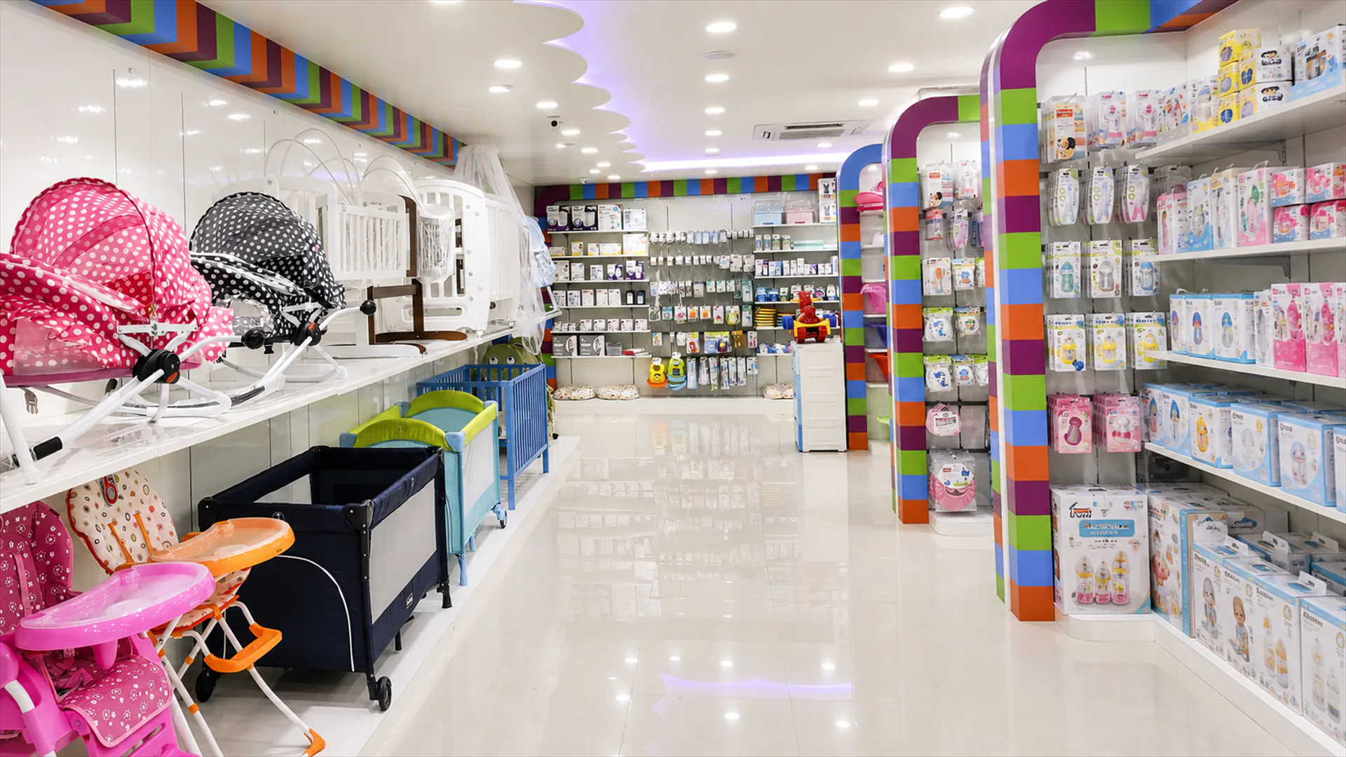 Wide hallway displaying cradles, baby furniture and accessories beneath patterned ceiling details.