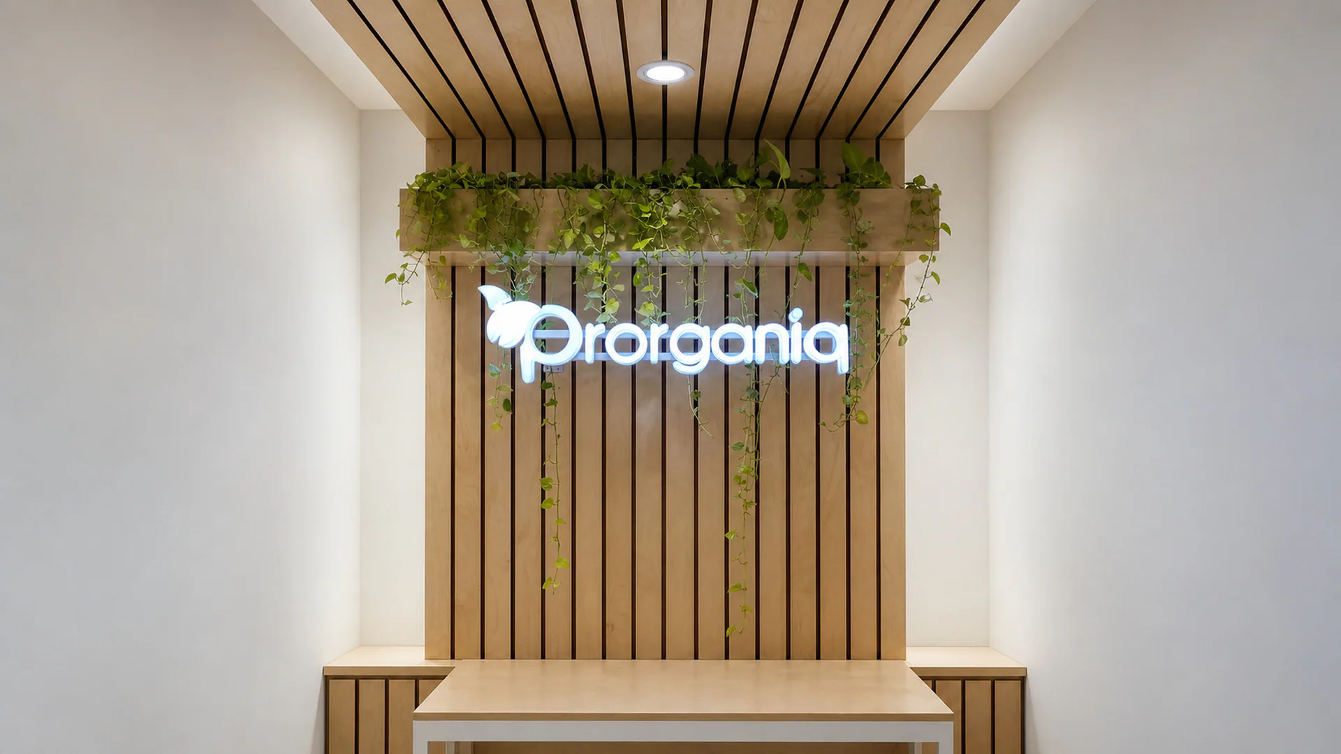 Illuminated Prorganiq logo on a vertical slatted wall with planting above.