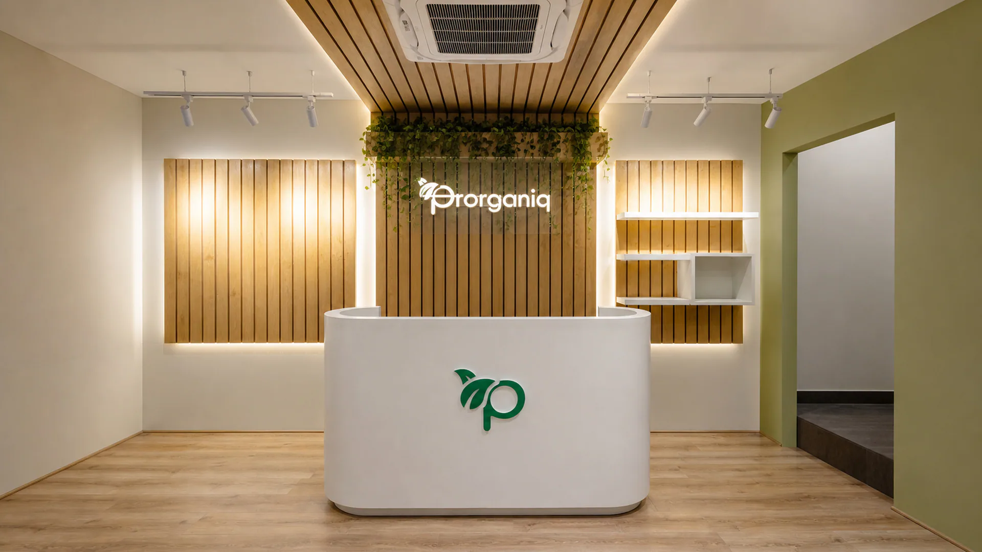 Front view of the curved reception desk and illuminated Prorganiq wall logo.