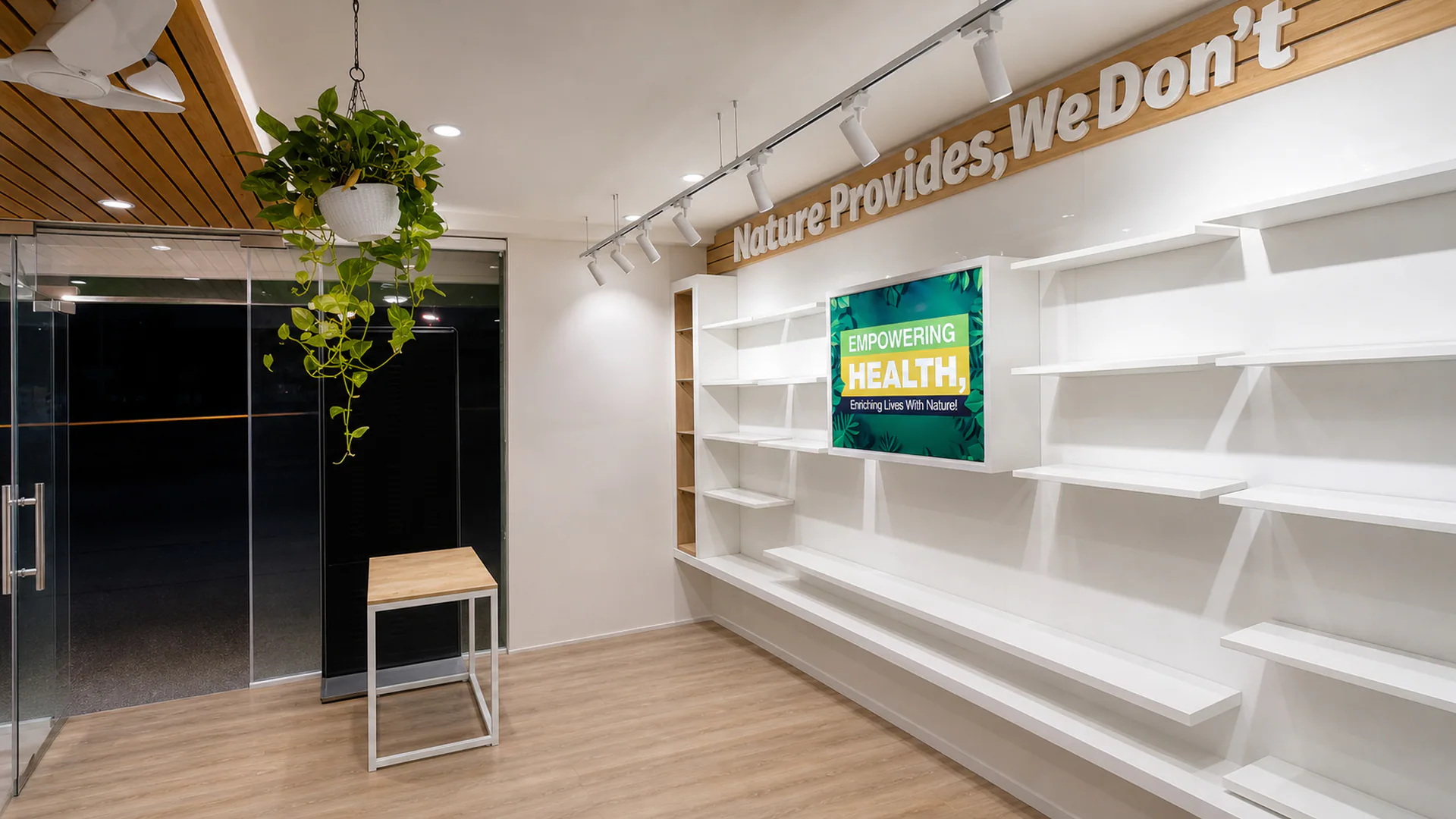 White display shelving beside hanging plants and the glazed entrance.