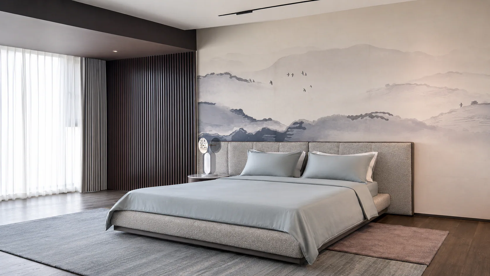 Bedroom with a pale upholstered bed and landscape artwork behind the headboard.