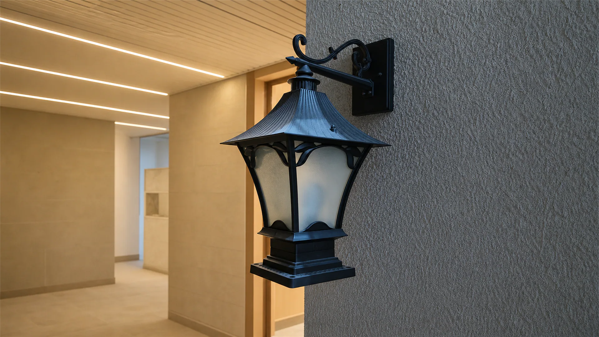 Black wall-mounted lantern against a textured wall beside a warm timber-lined passage.