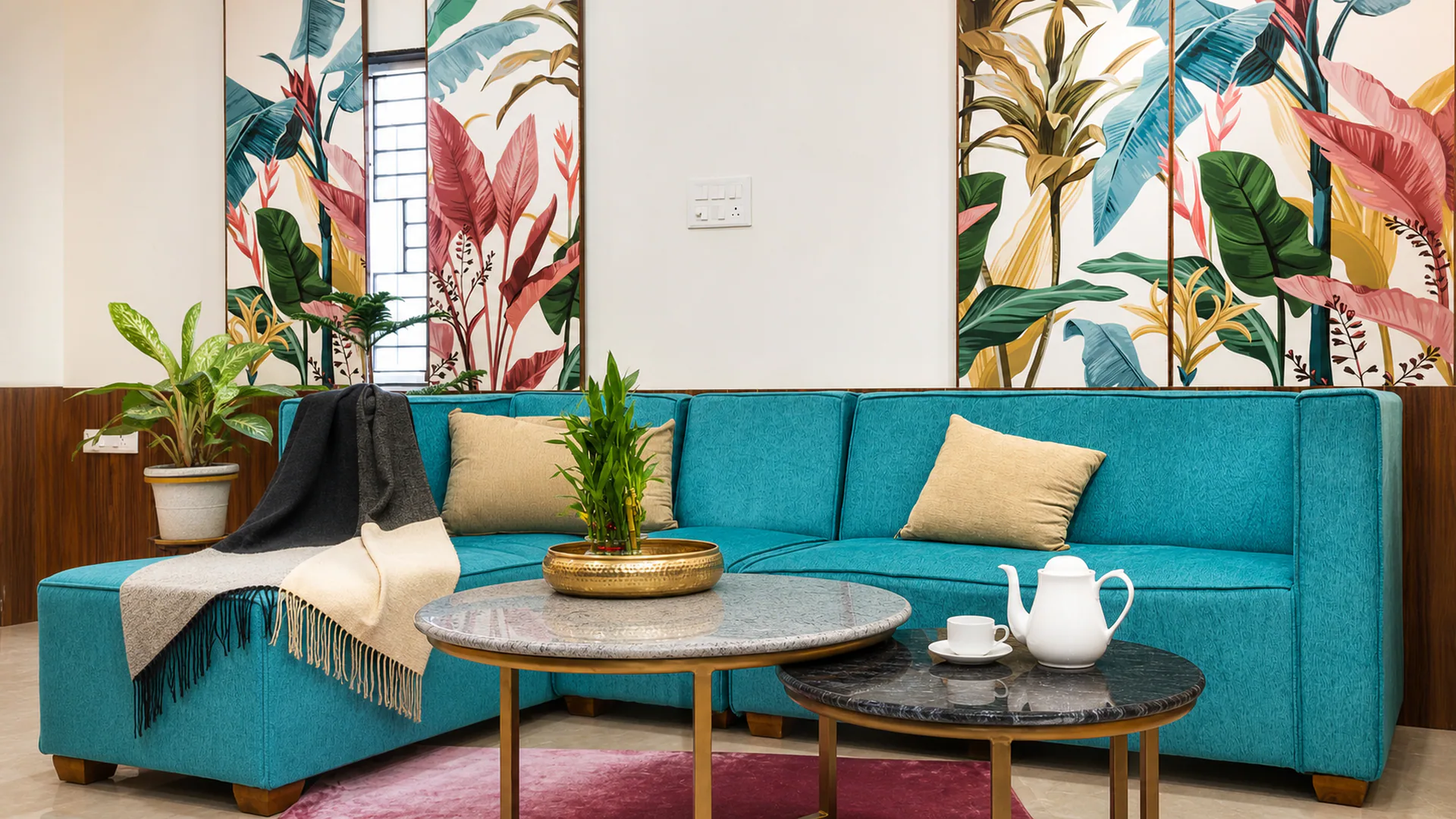 Front view of a turquoise sofa beneath three botanical wall panels.
