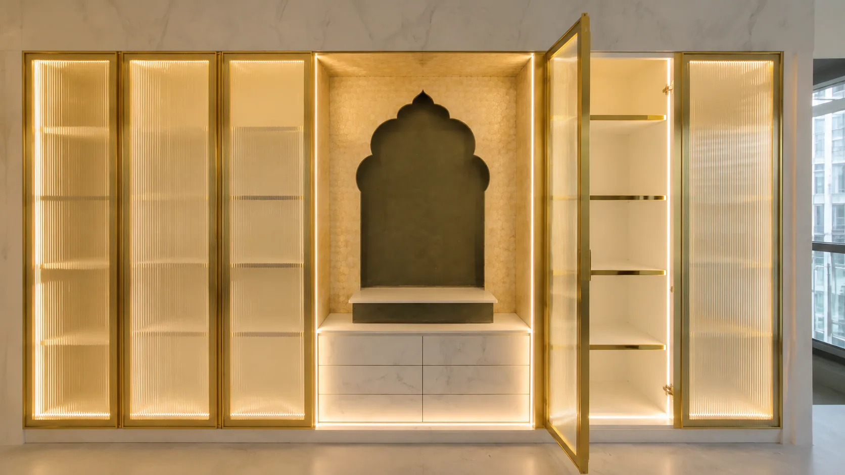 Illuminated arched wall niche set within a built-in cabinet.